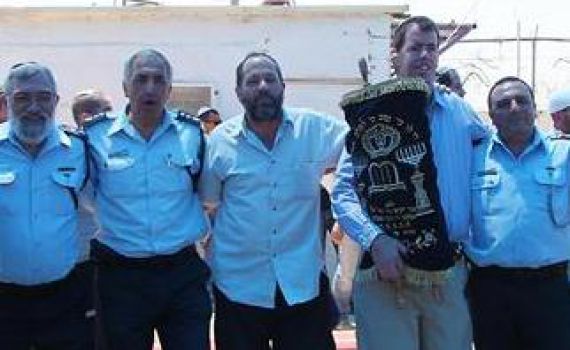 שוטרים ומתיישבים רוקדים יחד בחברון עם ספר התורה