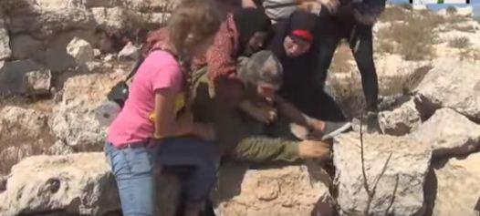 ביזיון: פלסטיניות מכות חייל שאינו יכול להגיב