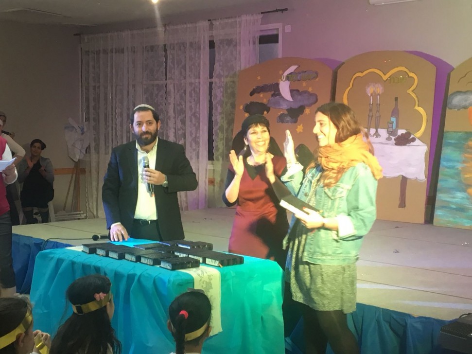 אחת הגרות מקבלת סידור מרב הישוב יקיר ומנהלת בית הספר2