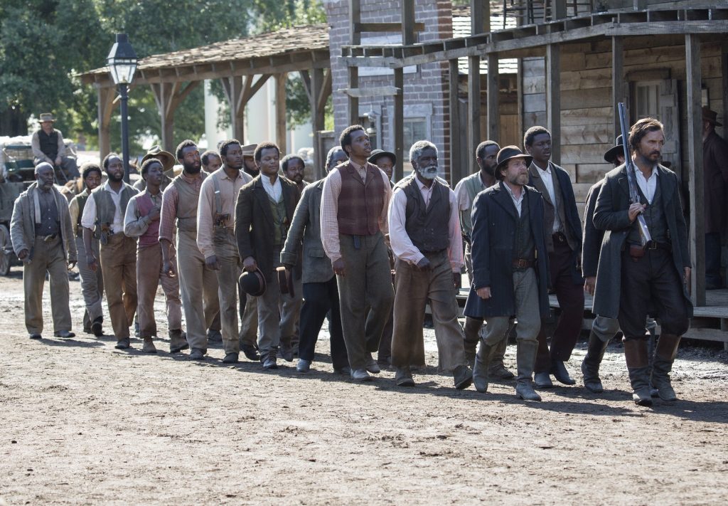 Newt (Matthew McConaughey) and his men march into town on election day to cast their votes at the Alice Hotel.