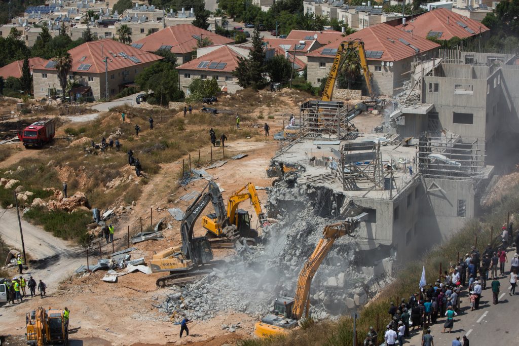 A tractor demolish two buildings in the Israeli settlement of Beit El, near the West Bank city of Ramallah, on July 29, 2015, following the High Court's decision to upheld an earlier order to demolish the buildings in the settlement. The High Court determined the housing units had been built on private Palestinian land seized by the IDF in the 1970s. Photo by Yonatan Sindel/Flash90 *** Local Caption *** ôéðåé áéú àì îúðçìéí äúðçìåú èøè÷åø