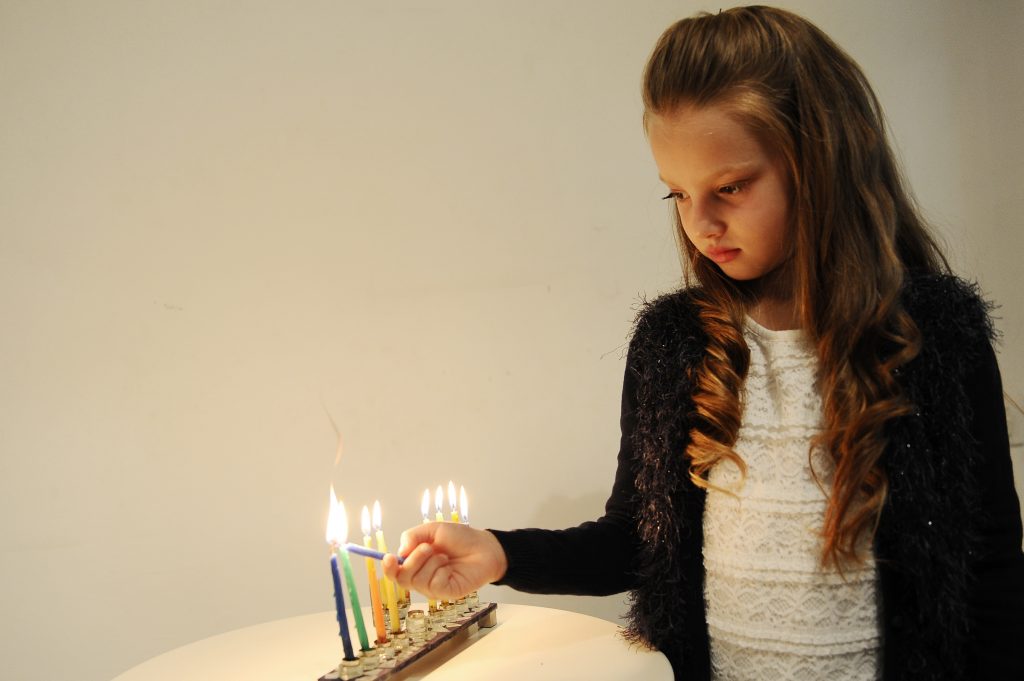 Illustration of a young Jewish girl lighting the Hanucka candles for the Jewish holiday of Hanukkah. The Hanukkah festival is observed by the kindling of the lights of a 'hanuckia'- a nine-branched candelabrum, with one additional light being lit on each night of the holiday. November 27, 2013. Photo by Mendy Hechtman/Flash90 *** Local Caption *** ðøåú ðø çðåëä ìäãìé÷ ðøåú éìãä çðåëéä